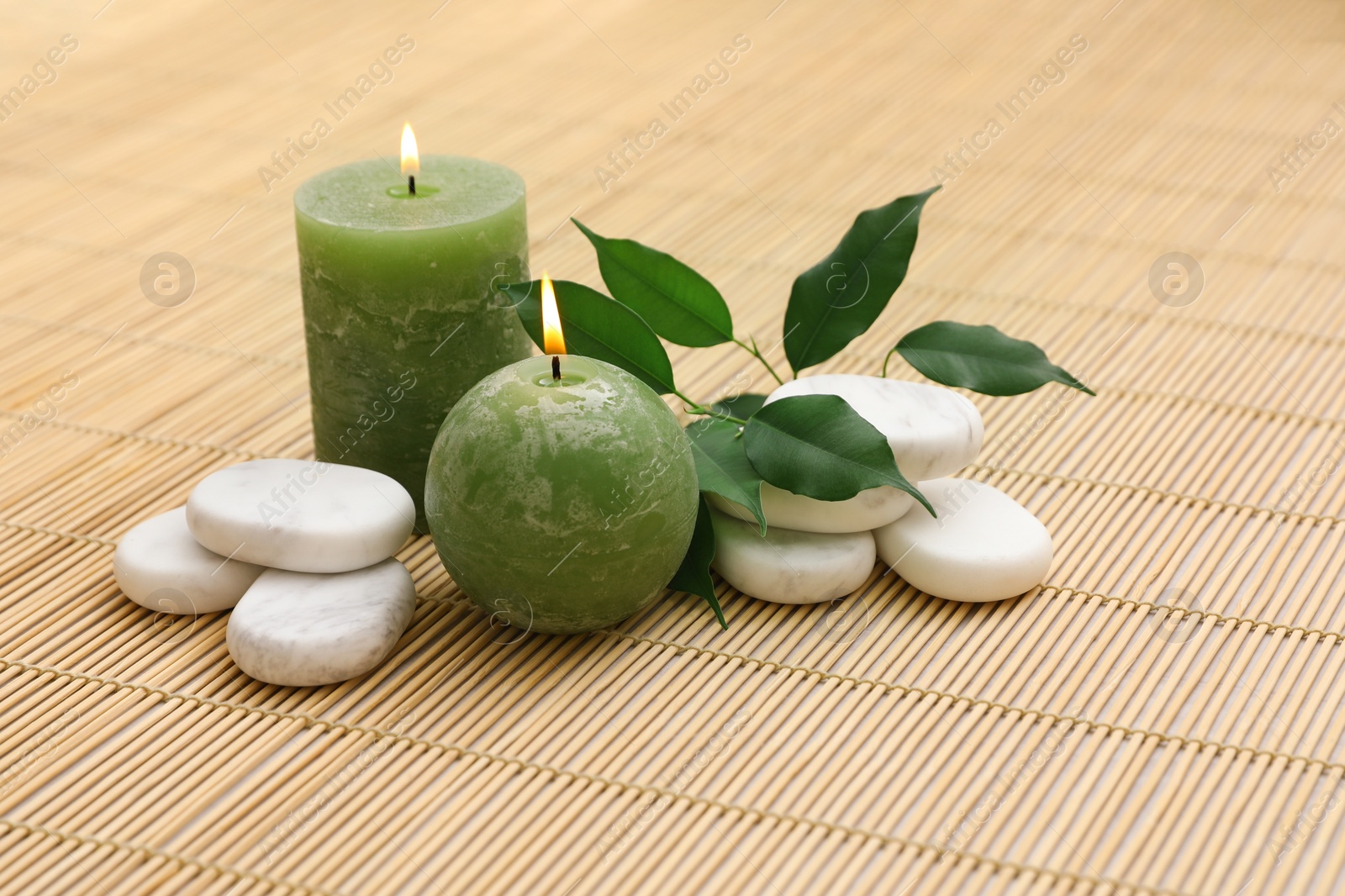 Photo of Composition with spa stones and candles on bamboo mat