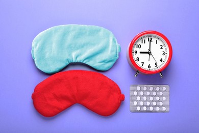 Photo of Soft sleep masks, pills and alarm clock on purple background, flat lay