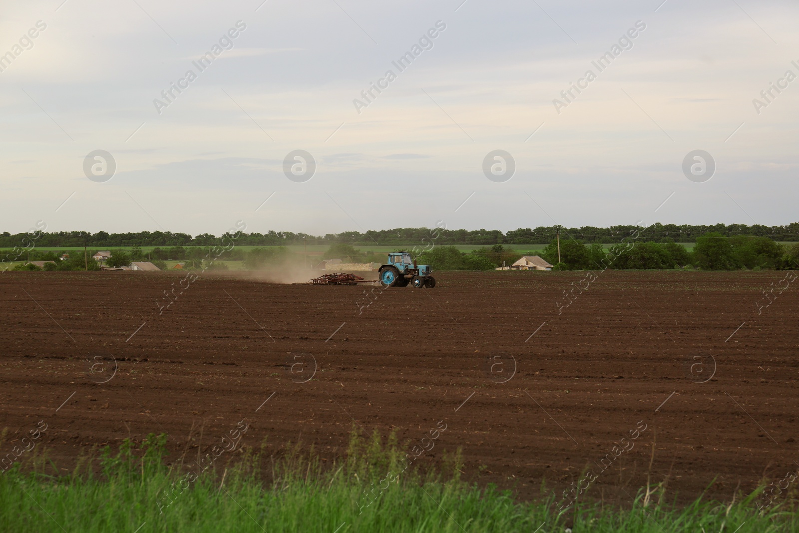 Photo of Tractor plowing agricultural field under cloudy sky