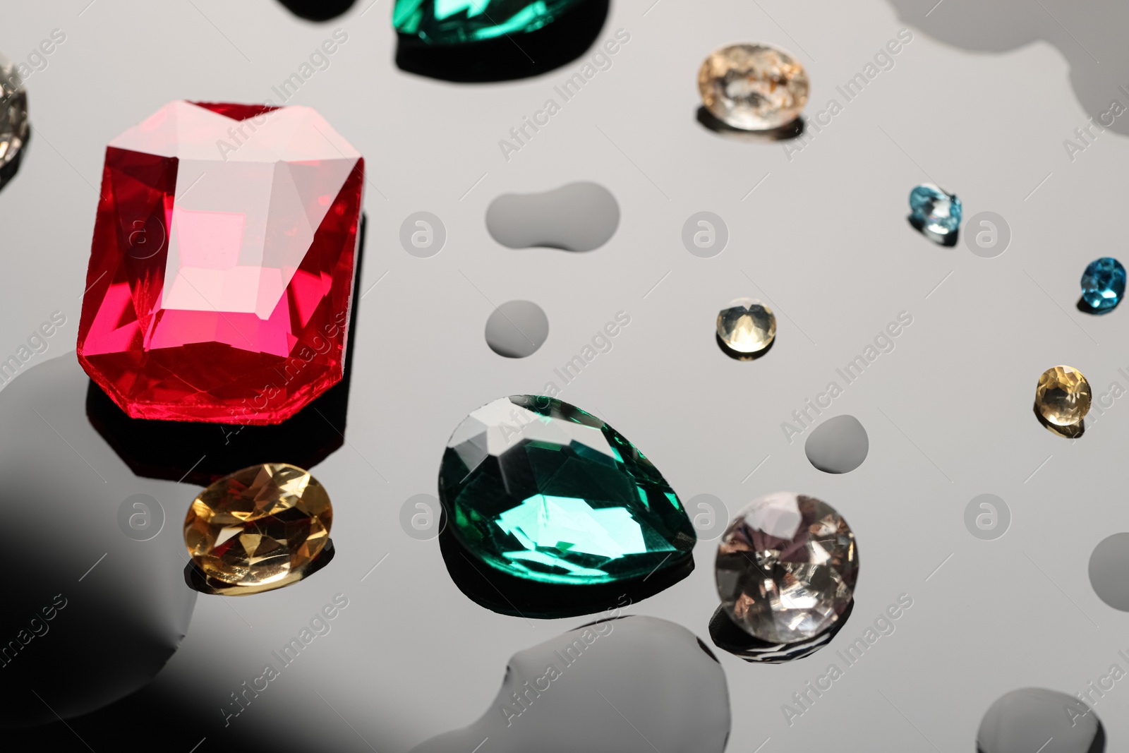 Photo of Different beautiful gemstones for jewelry on dark surface with drops