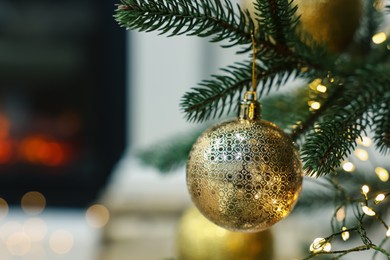 Photo of Beautiful Christmas bauble hanging on fir tree branch in room, closeup. Space for text