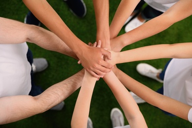 Group of volunteers joining hands together outdoors, top view