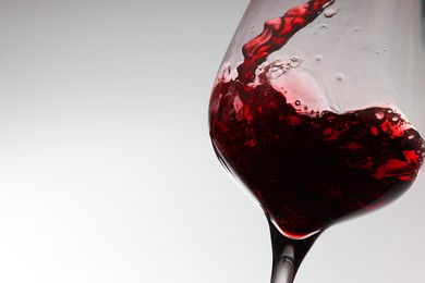 Tasty red wine in glass on white background, closeup. Space for text