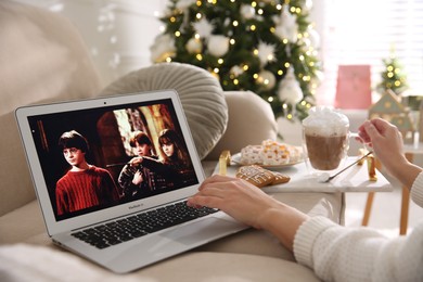Photo of MYKOLAIV, UKRAINE - DECEMBER 25, 2020: Woman watching Harry Potter movie on laptop at home, closeup. Cozy winter holidays atmosphere