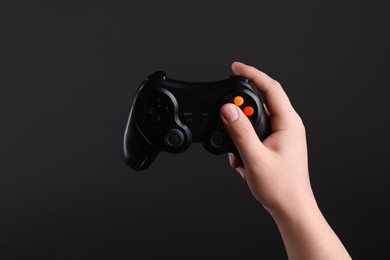 Photo of Woman using wireless game controller on dark background, closeup