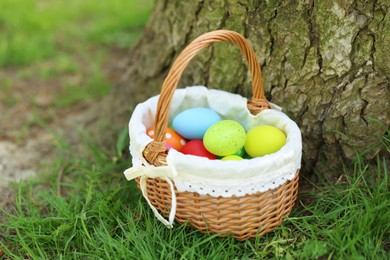 Photo of Easter celebration. Painted eggs in wicker basket on green grass