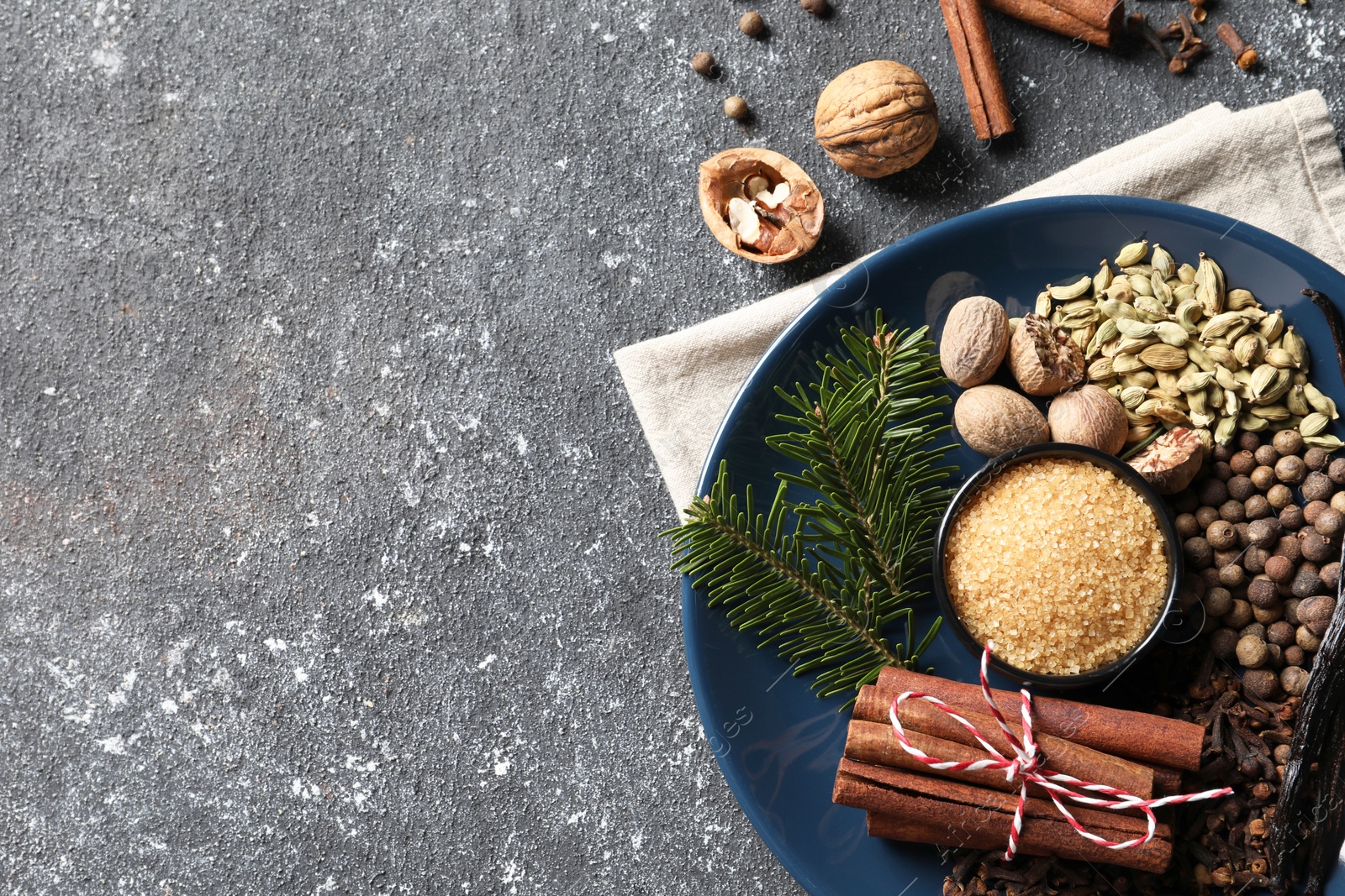 Photo of Different aromatic spices and fir branches on grey textured table, flat lay. Space for text