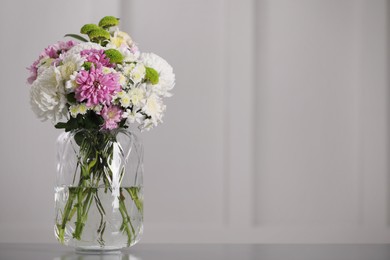 Photo of Bouquet of beautiful chrysanthemum flowers in vase on table, space for text