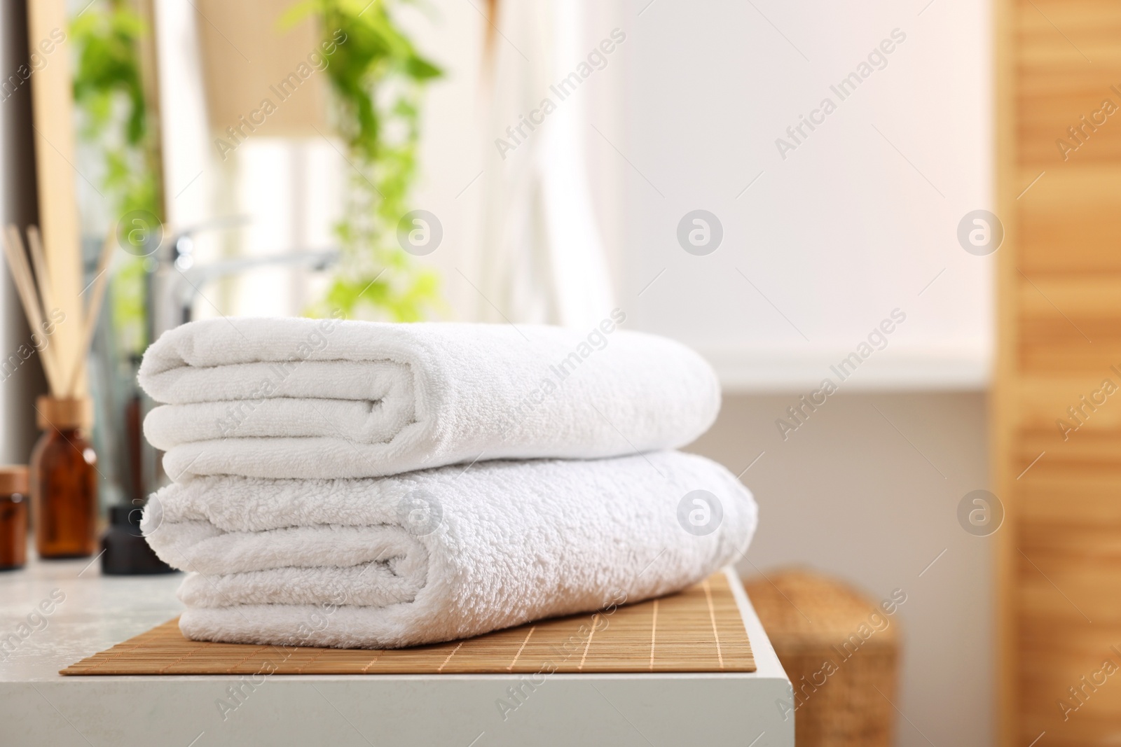 Photo of Stacked soft towels on white table in bathroom. Space for text