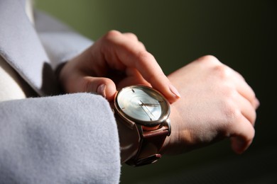 Photo of Woman with luxury wristwatch on dark background, closeup