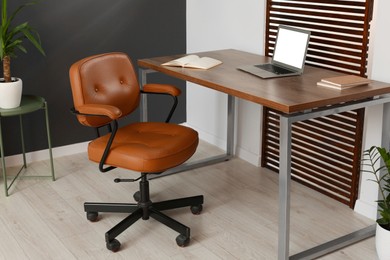 Photo of Stylish office interior with comfortable chair, desk and laptop