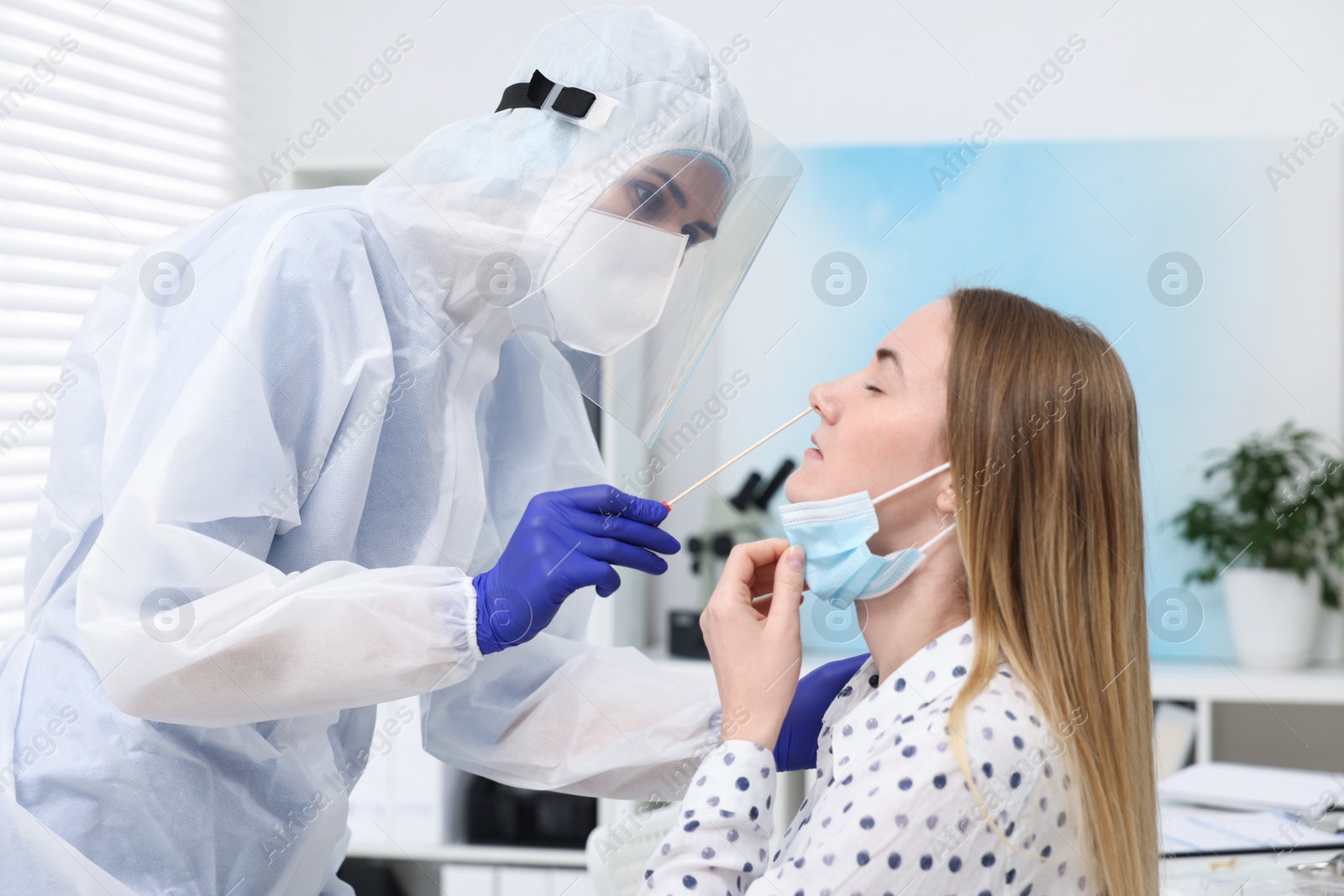 Photo of Laboratory testing. Doctor in uniform taking sample from patient's nose with cotton swab at hospital