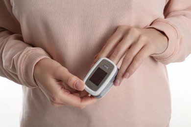 Woman using pulse oximeter for oxygen level testing on white background, closeup
