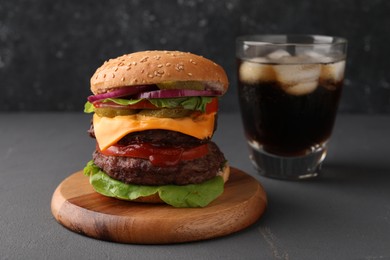 Photo of Tasty cheeseburger with patties and soda drink on grey table
