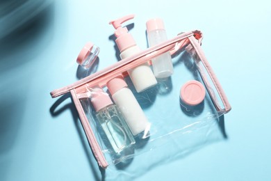 Photo of Cosmetic travel kit with plastic bag on light blue background, top view