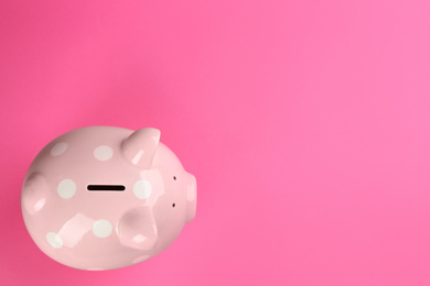 Photo of Piggy bank on pink background, top view. space for text