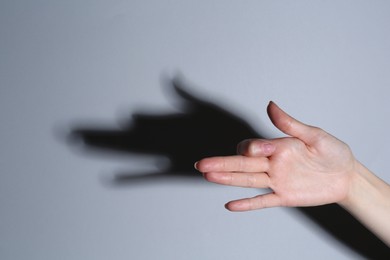 Photo of Shadow puppet. Woman making hand gesture like dog on grey background, closeup