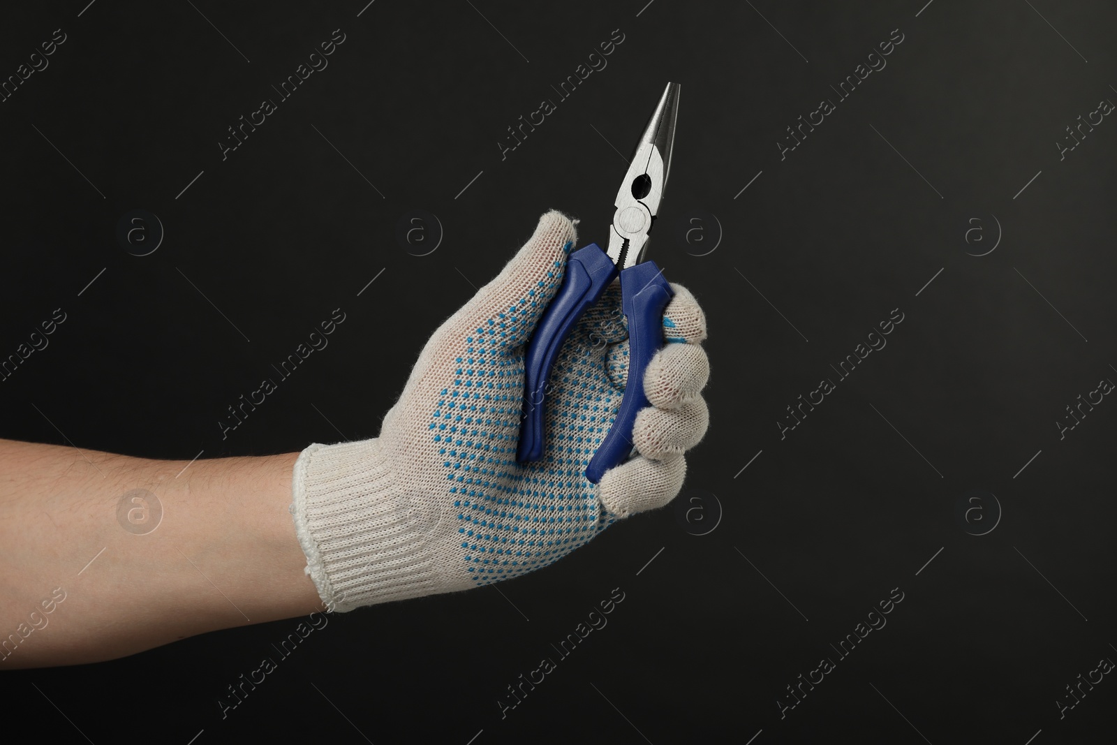 Photo of Man with needle nose pliers on black background, closeup