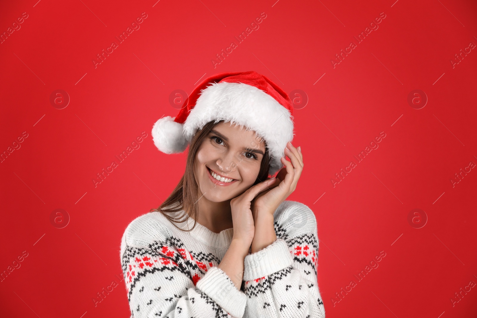 Photo of Pretty woman in Santa hat and Christmas sweater on red background