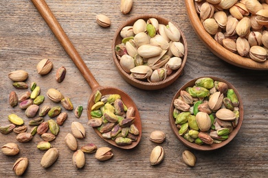 Photo of Composition with organic pistachio nuts on wooden table, top view