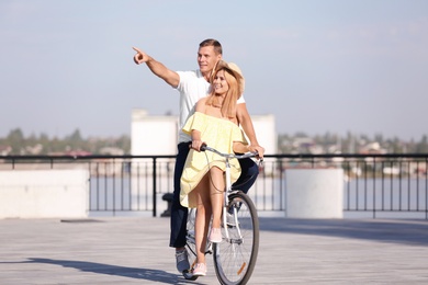 Photo of Happy couple riding bicycle outdoors on sunny day