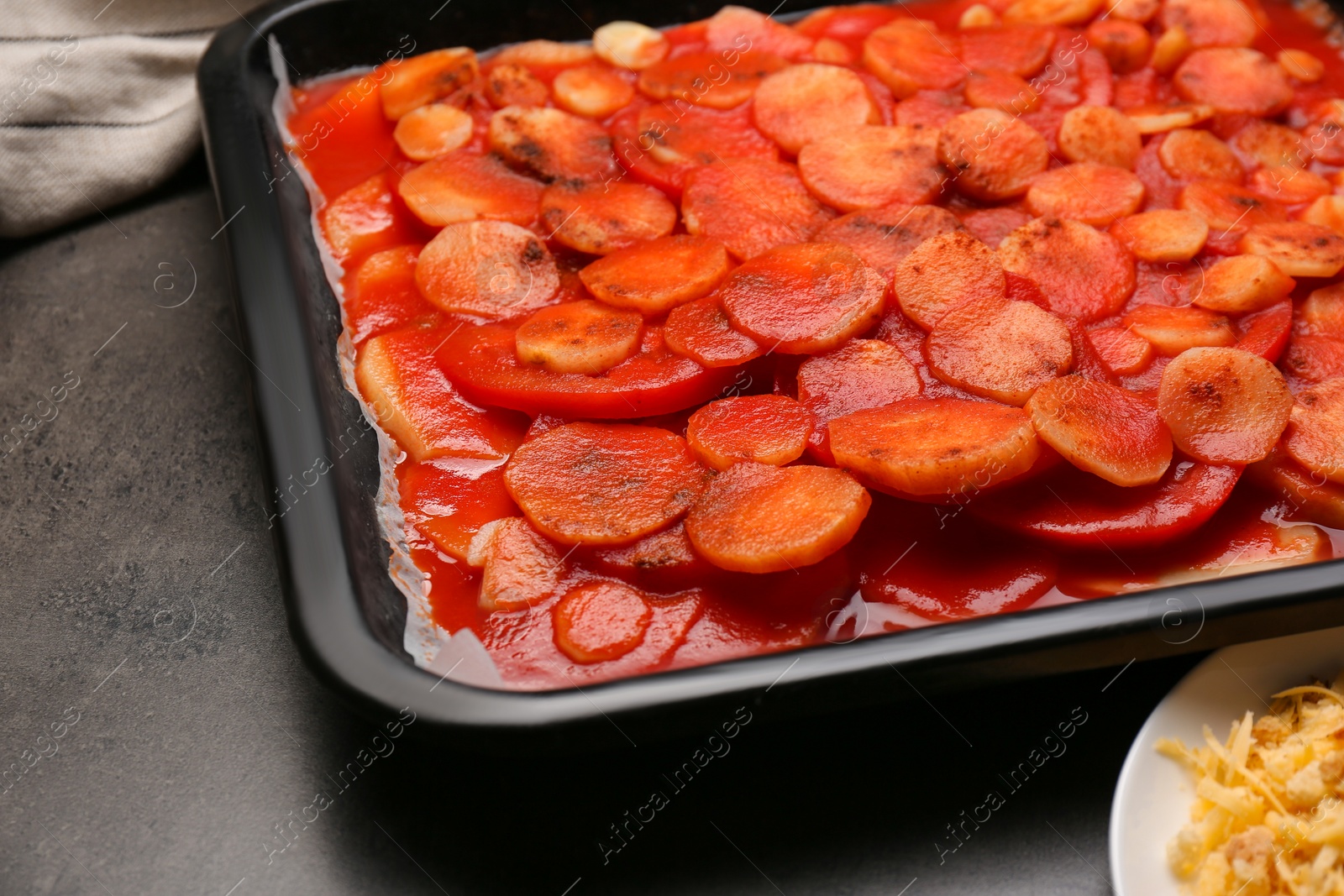 Photo of Tasty parsnips with sauce on dark grey textured table, closeup