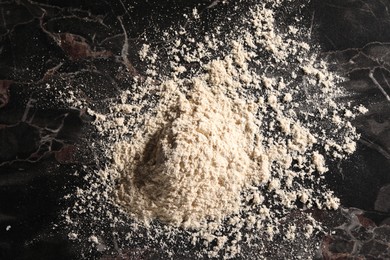 Photo of Pile of flour on black marble table, above view