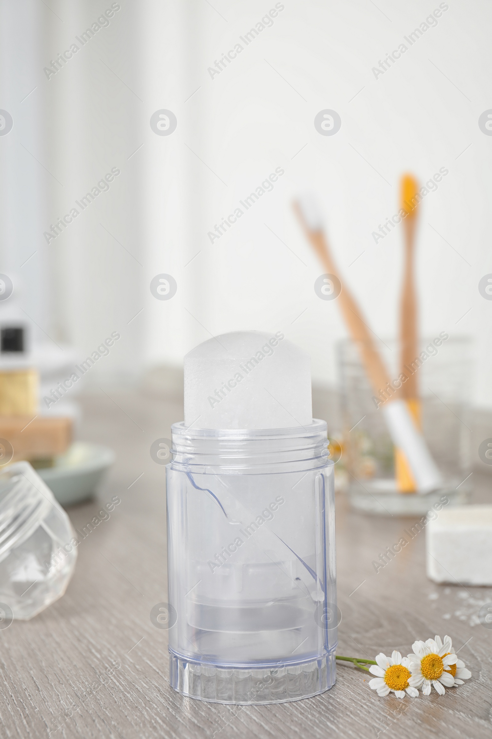 Photo of Natural crystal alum deodorant and chamomile flowers on wooden table