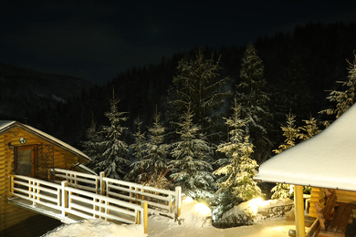 Photo of Modern cottage and wooden gazebo near snowy forest at evening