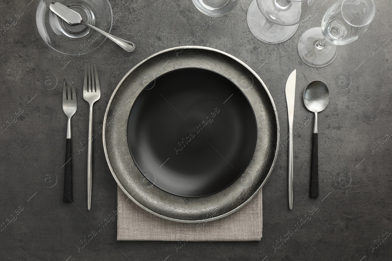 Photo of Stylish setting with cutlery, glasses and plates on black table, flat lay