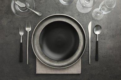 Stylish setting with cutlery, glasses and plates on black table, flat lay