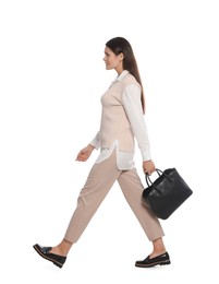 Young woman with stylish leather bag walking on white background