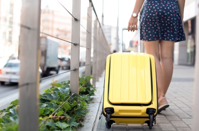 Photo of Young woman with yellow carry on suitcase outdoors