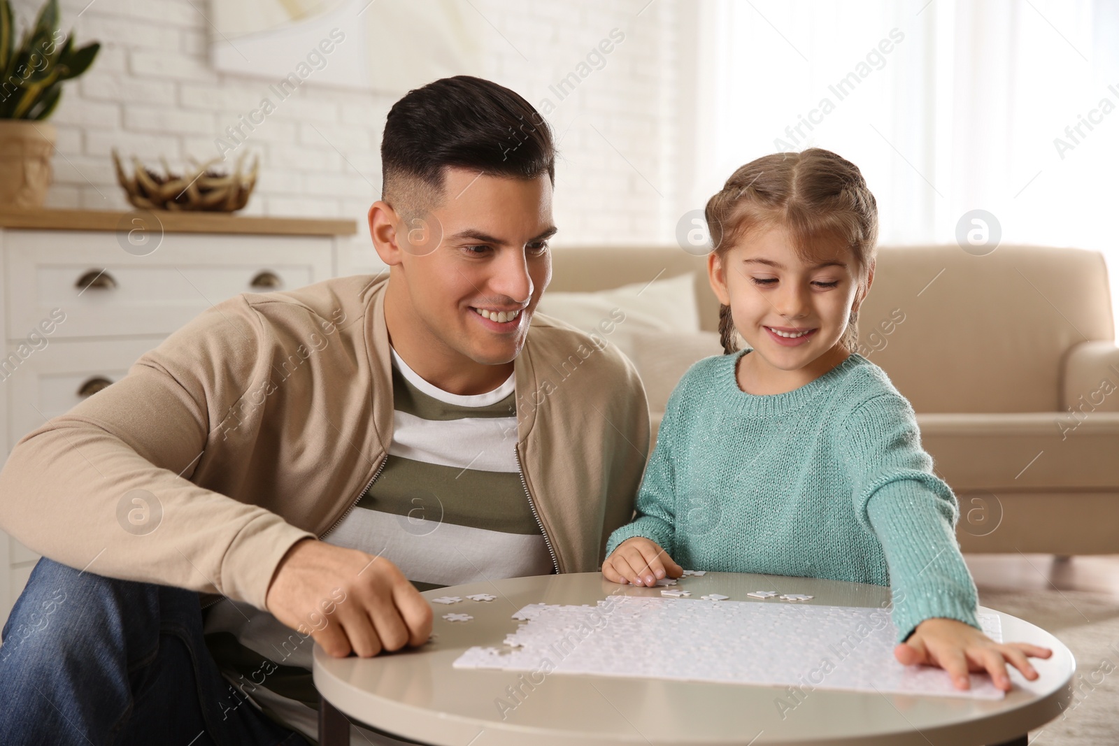 Photo of Happy father and his daughter playing with puzzles at home