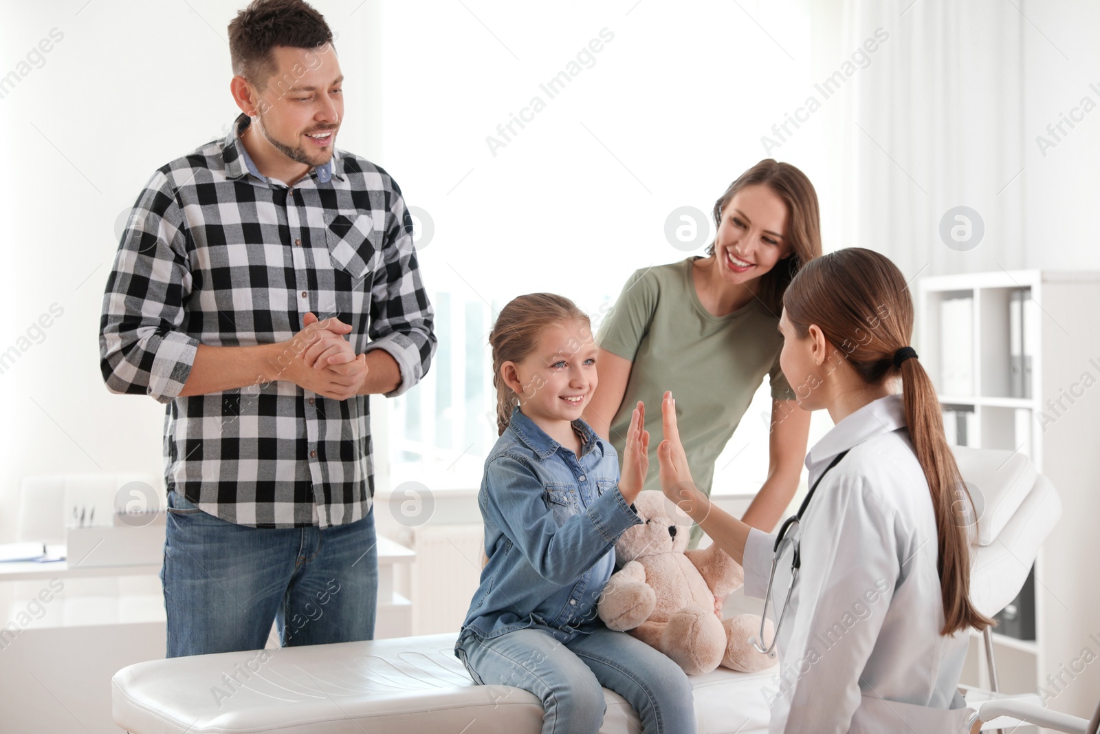 Photo of Parents and daughter visiting pediatrician. Doctor working with patient in hospital