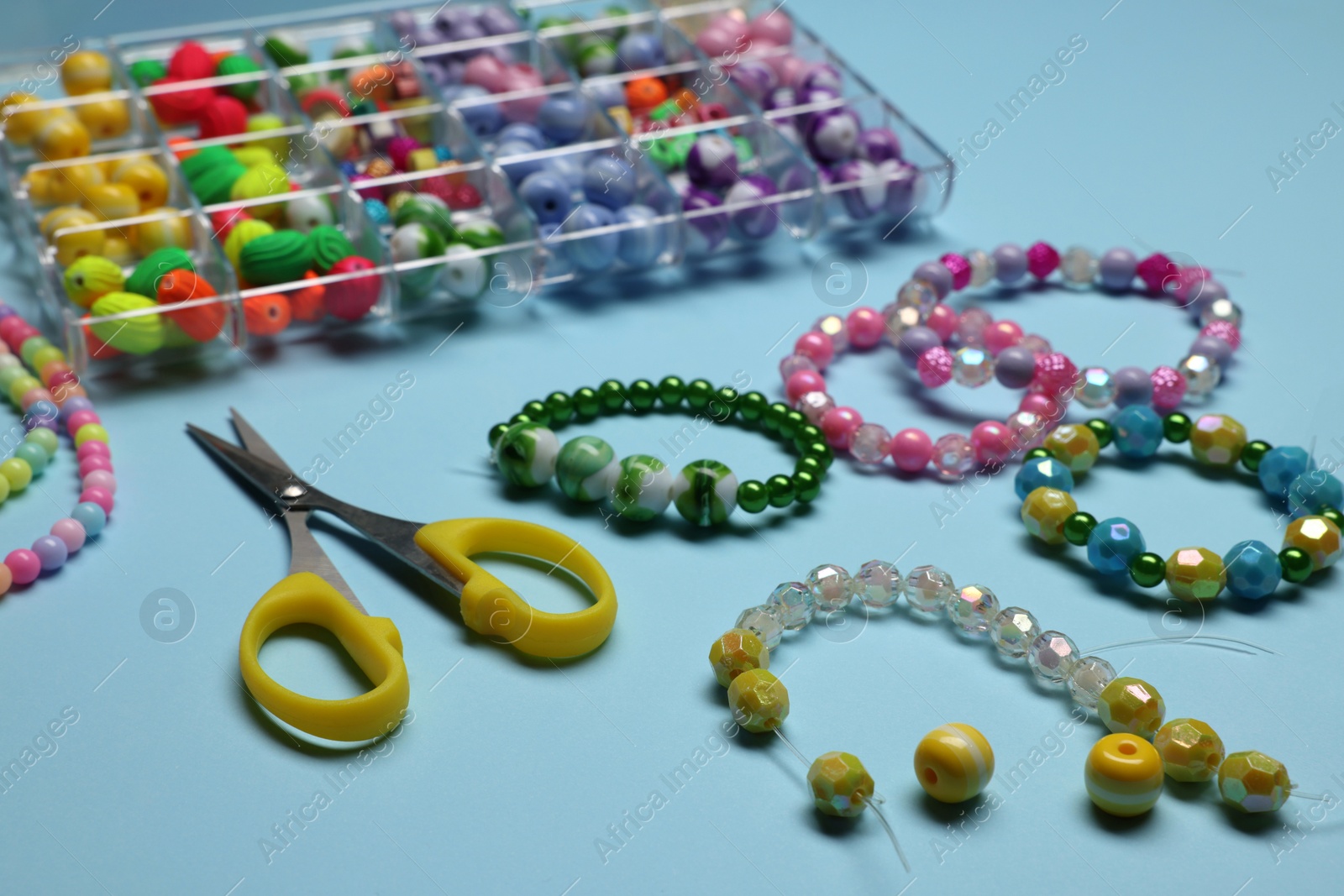 Photo of Composition with different colorful beads on light blue background