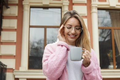 Young woman with cup of hot drink outdoors