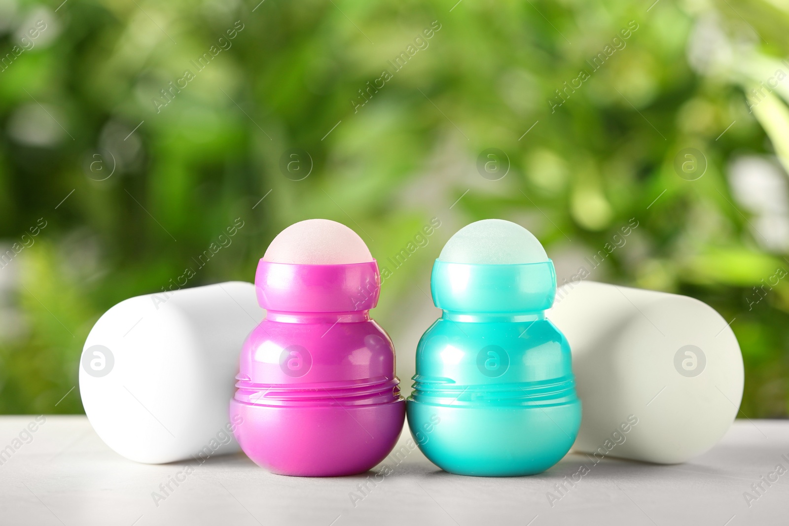 Photo of Different deodorants on white wooden table against blurred background