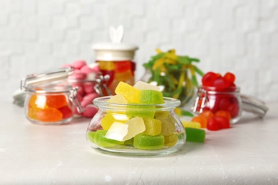 Glass jar with tasty jelly candies on light table