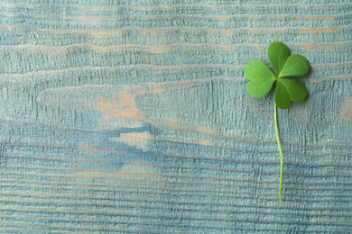 Photo of Clover leaf on blue wooden table, top view with space for text. St. Patrick's Day symbol