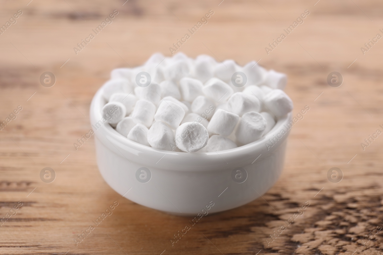 Photo of Bowl with delicious marshmallows on wooden table
