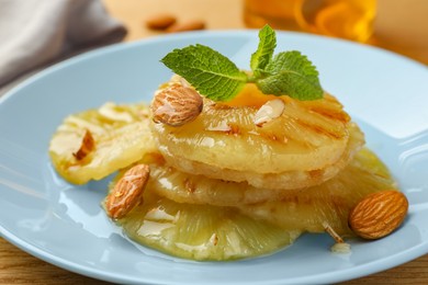 Photo of Tasty grilled pineapple slices, almonds and mint on plate, closeup