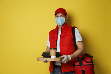 Courier in protective gloves and mask holding order on yellow background. Food delivery service during coronavirus quarantine