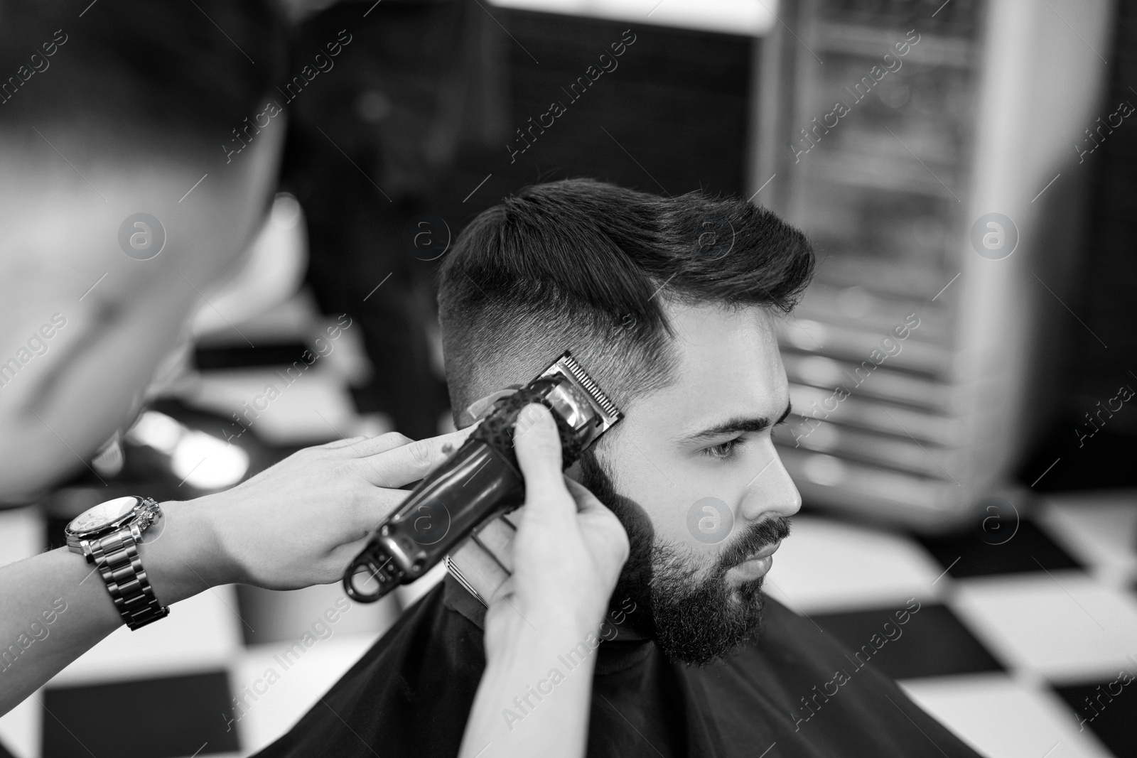 Image of Professional hairdresser working with client in barbershop. Black and white effect