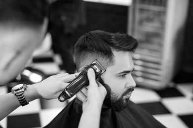 Professional hairdresser working with client in barbershop. Black and white effect