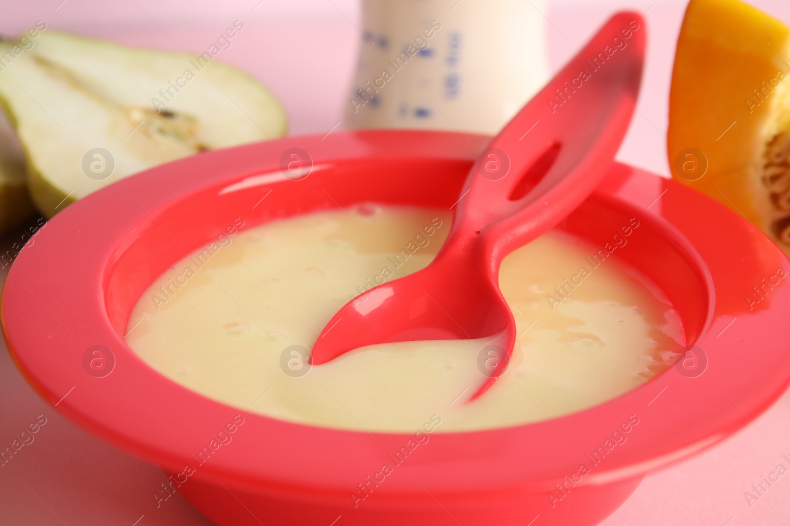 Photo of Baby food in bowl and fresh ingredients on pink background, closeup