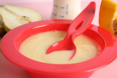 Photo of Baby food in bowl and fresh ingredients on pink background, closeup