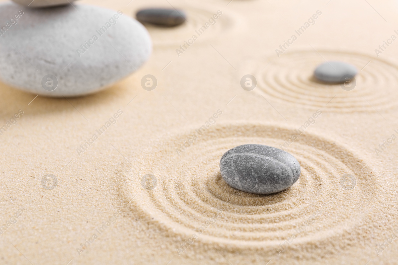 Photo of Zen garden stones on sand with pattern, closeup. Space for text