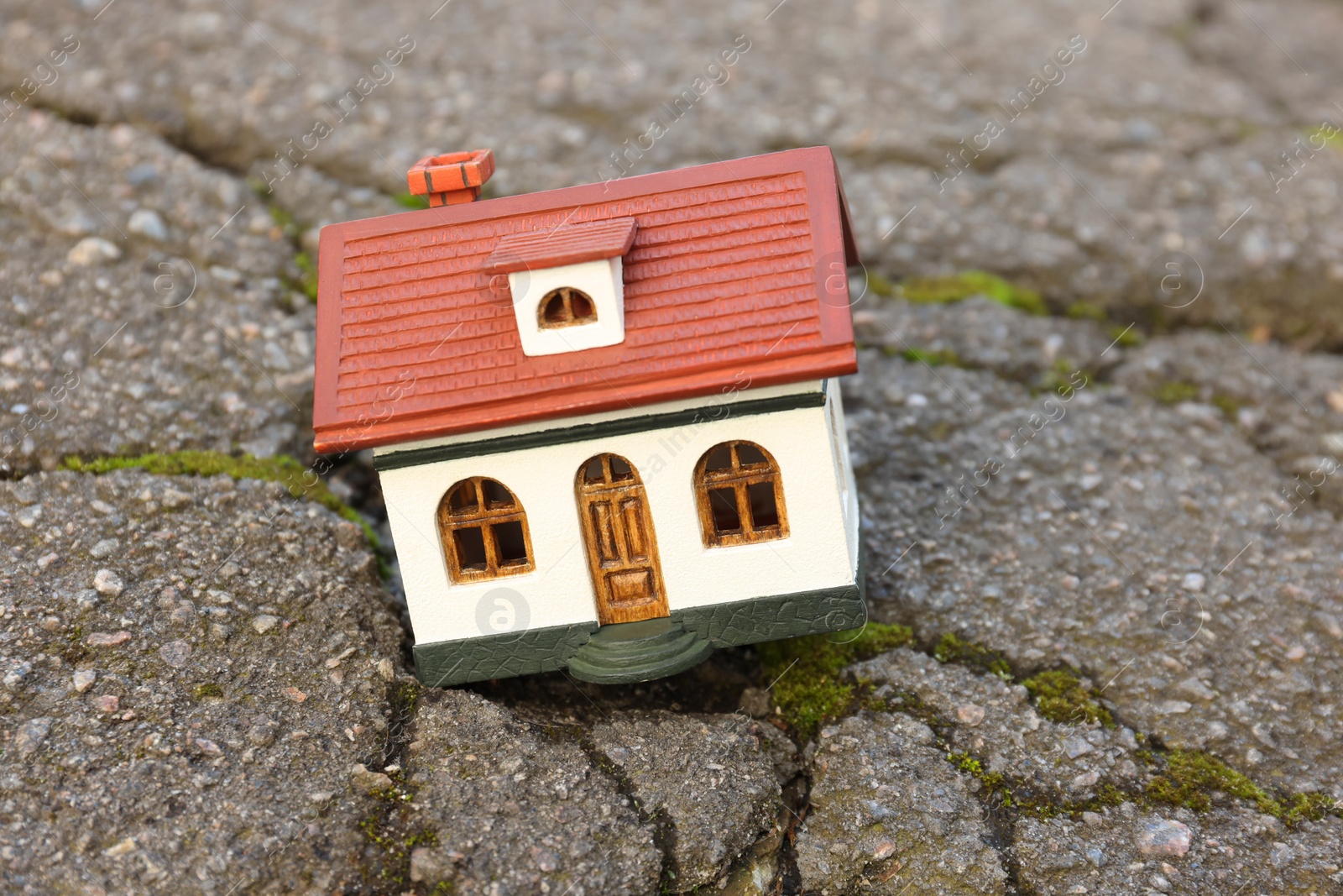 Photo of House model in cracked asphalt. Earthquake disaster