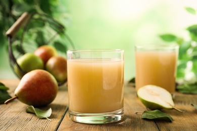 Photo of Fresh pear juice in glass on wooden table, closeup